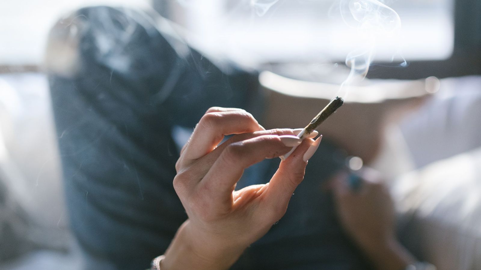 Hand mit Joint im Bett, warmes Licht